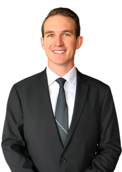Thomas Kaminski, a Physical Therapist Assistant, smiling in a black suit and tie on a neutral background.